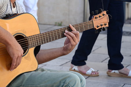 shallow focus photography of man using brown cutaway acoustic guitar