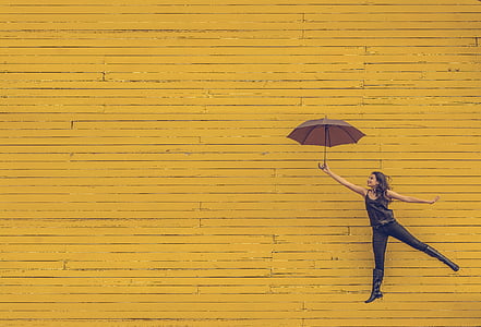 woman holding umbrella with yellow background