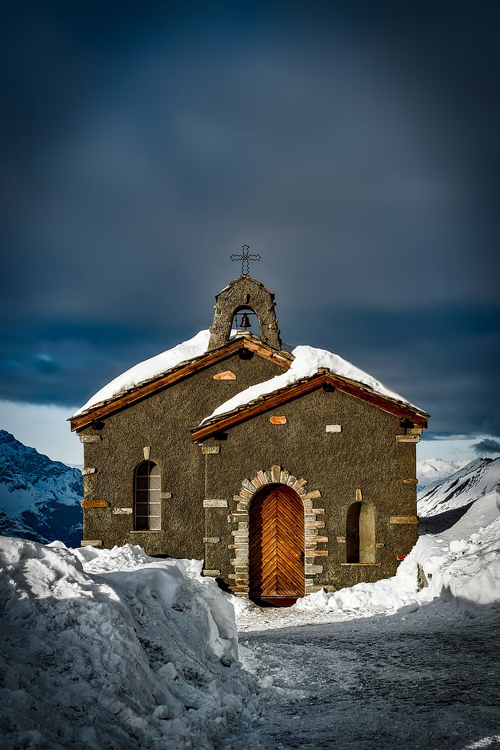 brown concrete chapel on snow coated mountain