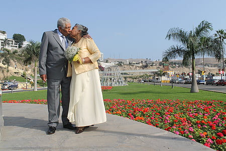 man wearing gray formal suit jacket and dress pants and woman wearing gold blazer and white maxi skirt