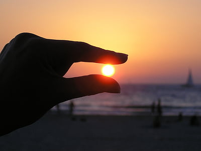 silhouette photo of sunset and person's hand