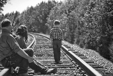 grayscale photo of three people on train railway