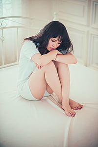 woman wearing white shirt sitting on white mattress