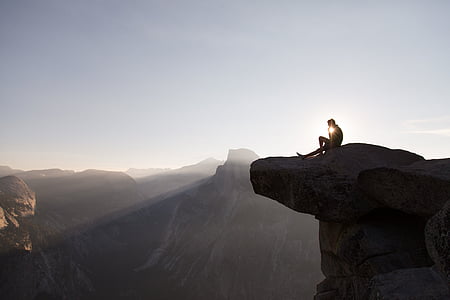 man sitting on top of mountain during daytime