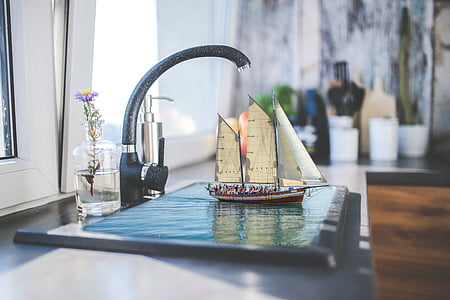 black faucet beside brown and white sailboat scale model