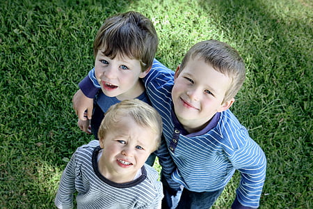 three children standing on grassy field