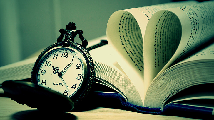 black and white pocket watch leaning on book