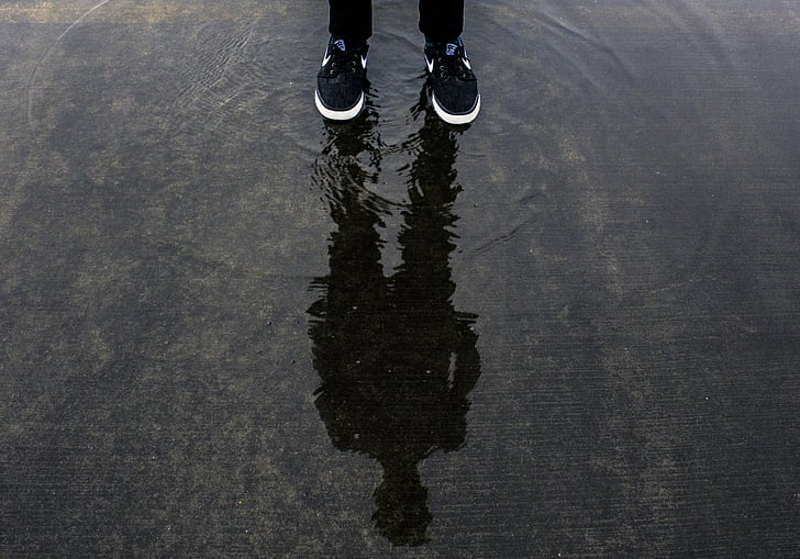 reflection of person on puddle during daytime
