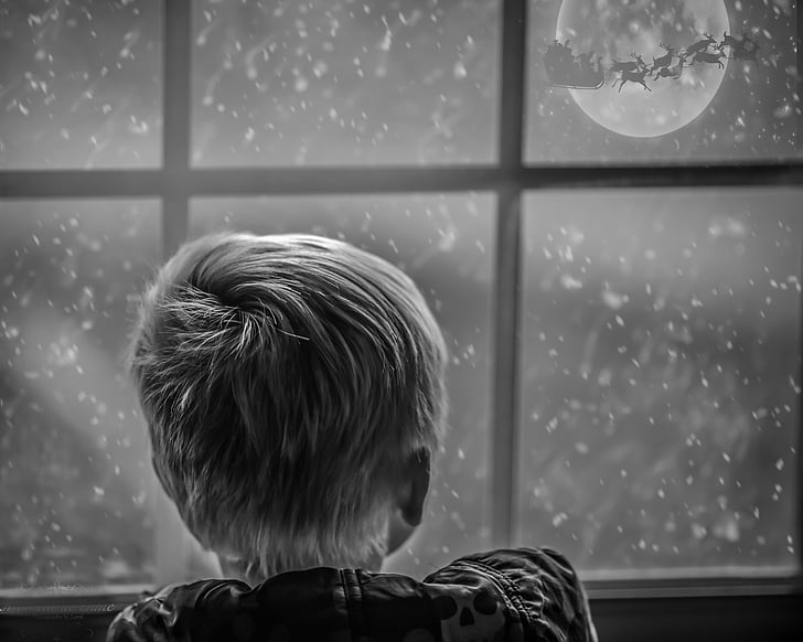 grayscale photo of boy leaning on window looking at moon during nighttime