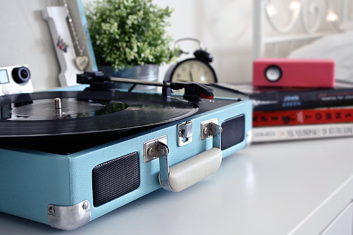 blue and black turntable beside black media player and red speaker place on white table