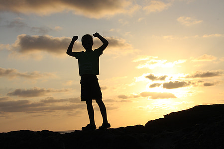 silhouette photo of boy on top of hill during daytime