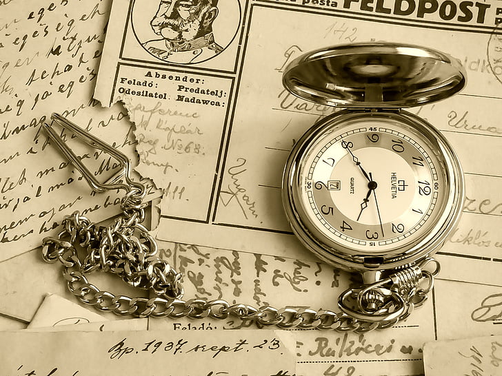 silver-colored pocket watch on white printed papers