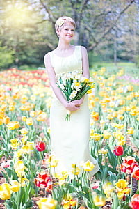 photograph of woman wearing yellow dress on a bed of flowers