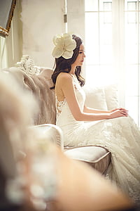 woman in white sleeveless floral wedding gown sitting on brown couch