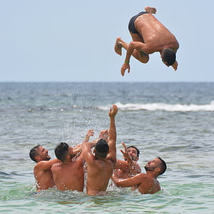 group of topless men in body of water under blue sky during daytime