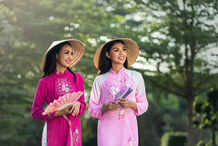 two women in pink cheongsam dresses during daytime