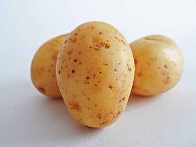 three yellow potatoes on white surface