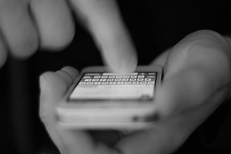 grayscale photograph of person holding white iPhone 4