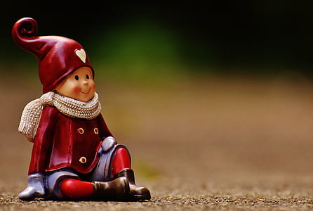 close up photo of red and blue boy sitting ceramic figurine