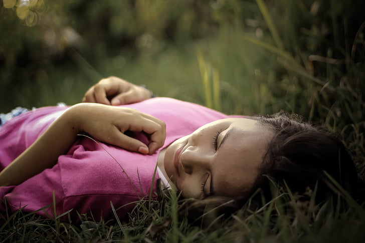 girl wearing pink top lying on grass