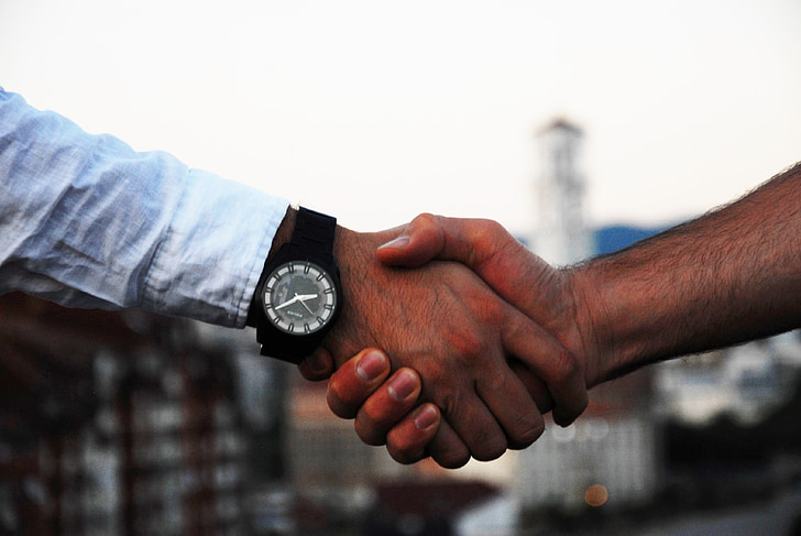 two persons shaking hands during daytime
