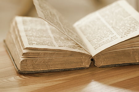 bible flipped open and placed on brown wooden board