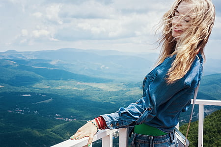 blonde haired woman wearing blue denim jacket overlooking mountain