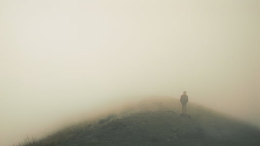 person standing on a foggy mountain
