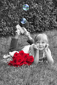 selective photography of red flowers near smiling girl