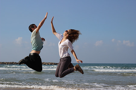 man and woman jumping photo in the sea