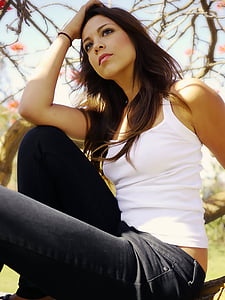 woman in white tank top and black jeans sitting during daytime