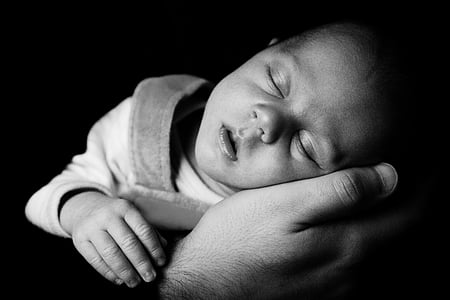 gray scale of baby sleeping on man's palm