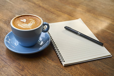 cup of espresso on saucer beside spiral note