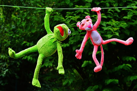 pink panther plush toy beside green frog plush toy hanging on rope