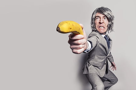 person wearing suit holding banana near wall