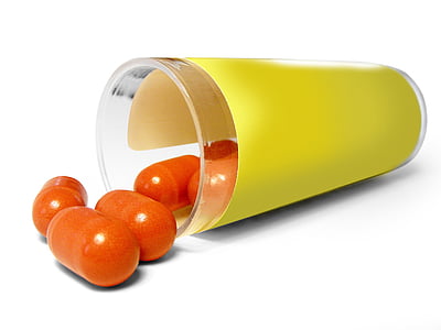 orange pills spilled on yellow glass container