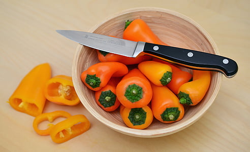 bowl of bell peppers with black handle kitchen knife