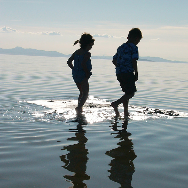boy and girl walking on the water during daytime