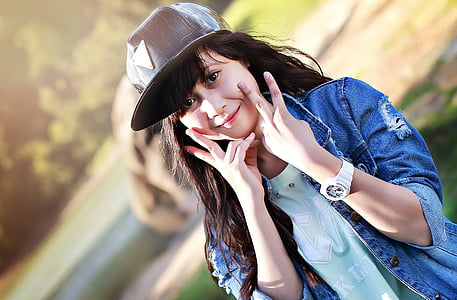 woman wearing blue denim jacket and black hat posing during daylight photography