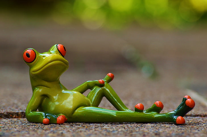 green ceramic frog figurine lying on gray concrete road in closed up photography