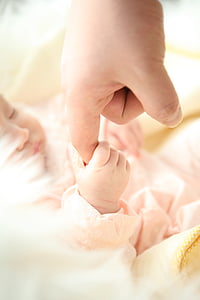 baby holding index finger of person