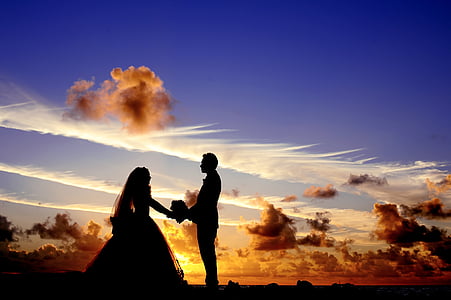 silhouette of couple standing under the clouds
