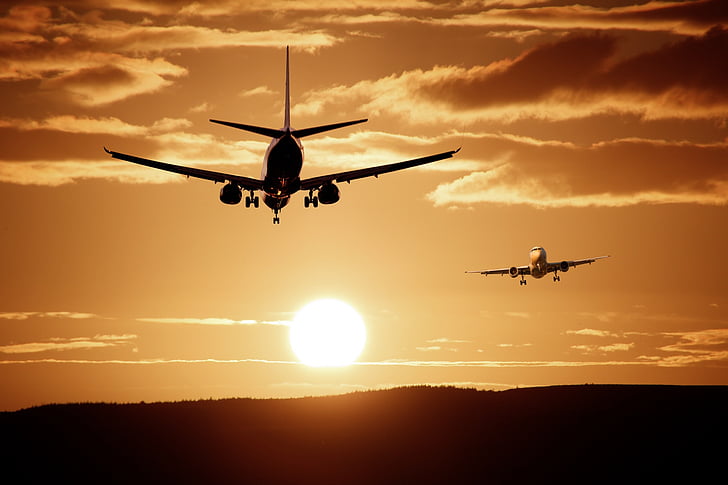 silhouette photo of two planes against the sun