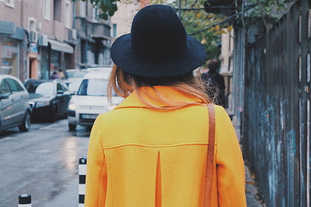woman in yellow coat with black hat