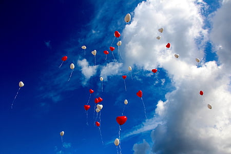 white and red heart balloons floating on sky