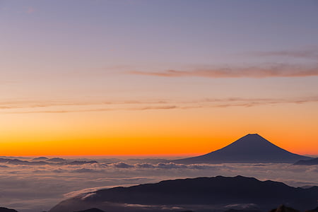 mountain above clouds during sunset