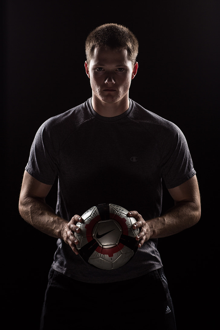 man wearing gray crew-neck t-shirt and holding gray and black Nike soccer ball