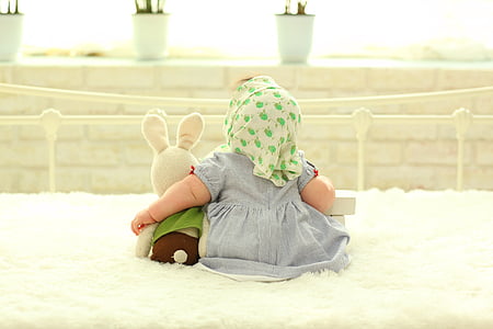 baby's gray dress near bunny plush toy
