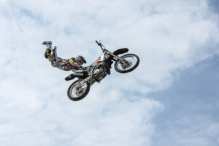 man wearing motocross gear doing superman stunt in mid air