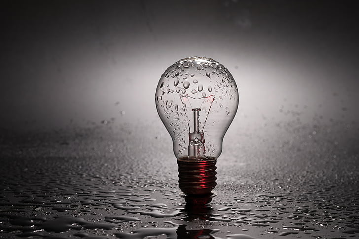 clear light bulb on gray surface with water droplets